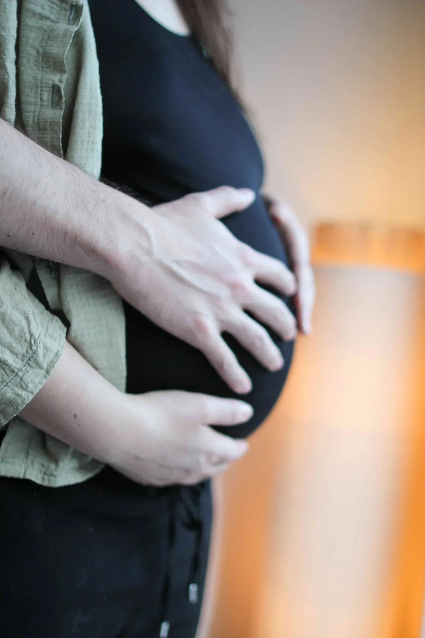 Un couple pose ses mains sur le ventre pendant la grossesse, un moment de connexion avec le bébé à venir